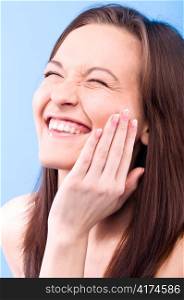 laughing beautiful woman is touching her face and looking at camera
