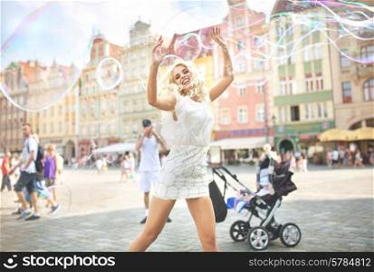 Laughing blond woman making soap bubbles