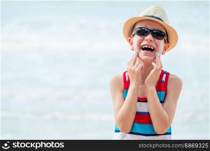 laughing boy 7 years smears face cream on the beach