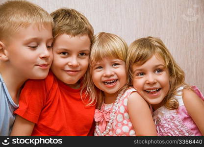 Laughing children four together in cosy room, two pretty girls and two boys