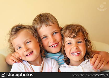 Laughing children three together in cosy room, two pretty girls and boy