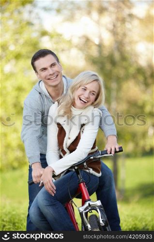 Laughing couple on a bike in the autumn park
