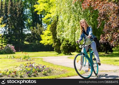 Laughing girl riding bicycle in the sunny park springtime