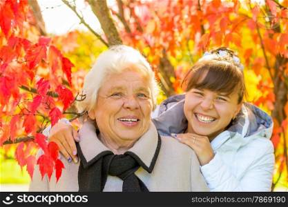 laughing grandmother and granddaughter in the park with beautiful red leaves