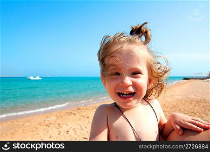 laughing little girl on sand beach near sea