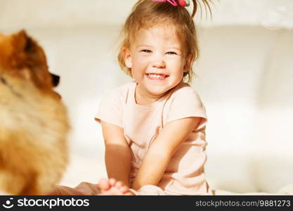 laughing Little girl. Portrait of beautiful baby girl playing with pomeranian dog