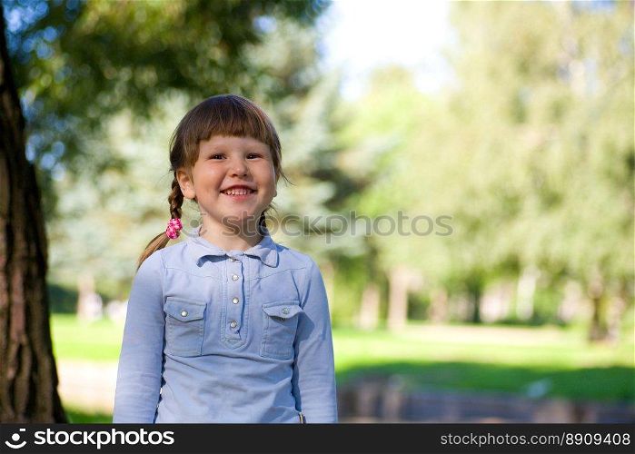 Laughing little girl standing near the tree