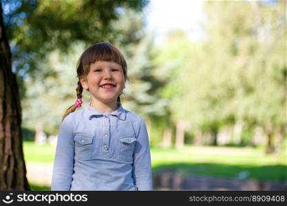 Laughing little girl standing near the tree
