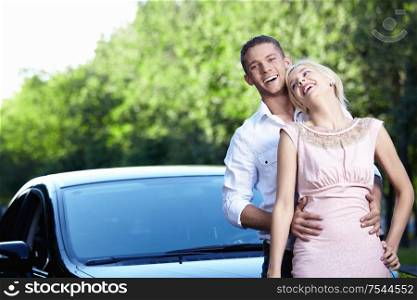 Laughing, loving couple beside car
