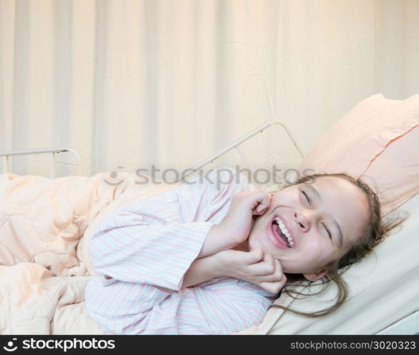 Laughing mixed race Asian American tween girl in hospital bed