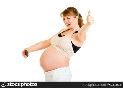 Laughing pregnant woman photographing her belly and showing thumbs up gesture isolated on white&#xA;