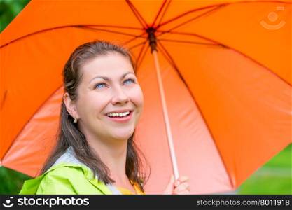 laughing pretty girl with an orange umbrella walking in the rain