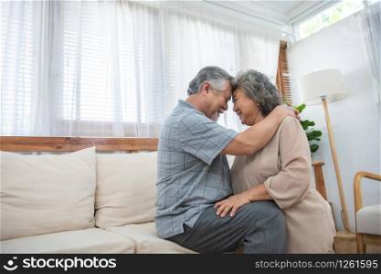 Laughing retirees pretty asian couple sitting on couch at home, spouses having candid healthy toothy smile, dental treatment check-up services for old people,medical insurance health care concept