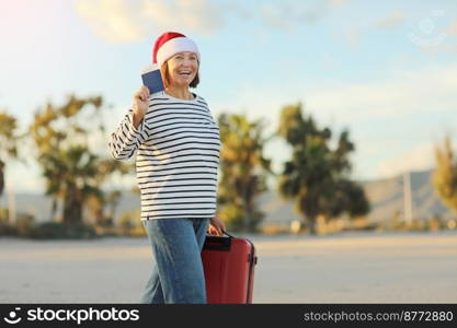 Laughing Santa adult woman in Christmas hat holding red suitcase, passport boarding pass ticket on palm trees background. Happy New Year 2023 celebration holiday concept. Winter vacation travel.. Laughing Santa adult woman in Christmas hat holding red suitcase, passport boarding pass ticket on palm trees background. Happy New Year 2023 celebration holiday concept. Winter vacation travel