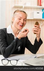 laughing secretary corrects make-up in the workplace in the office