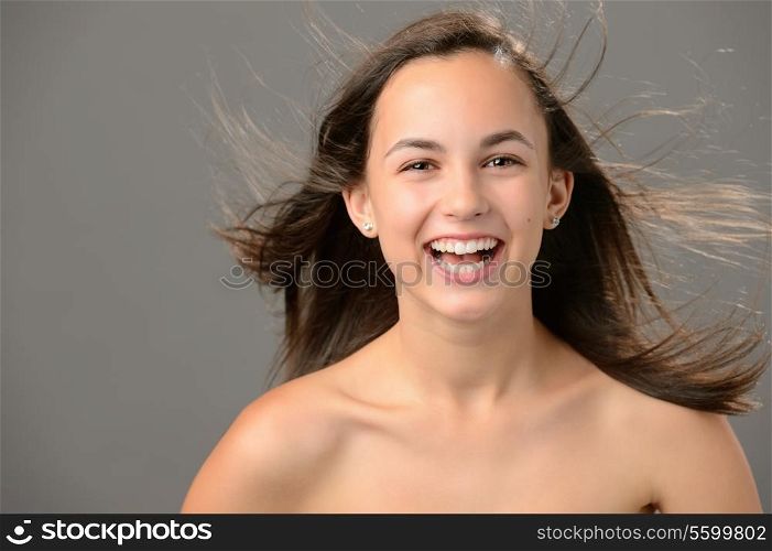 Laughing teenage girl blowing hair beauty skin on gray background