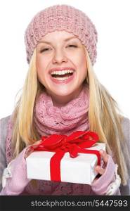 Laughing teenager girl in winter hat and scarf holding presenting box