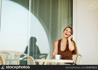 Laughing woman speaking mobile phone at terrace