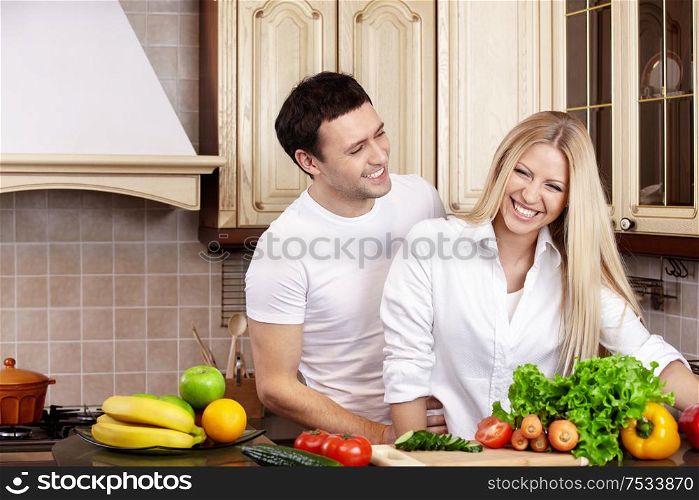 Laughing young couple in white on kitchen