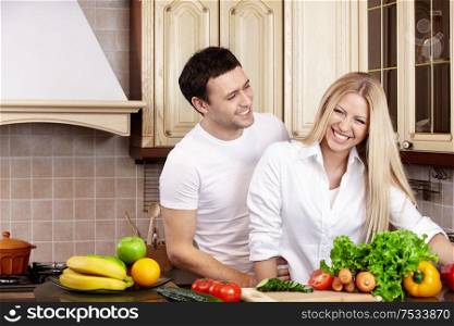 Laughing young couple in white on kitchen