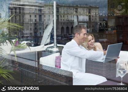 Laughing young couple looking at laptop in a restaurant