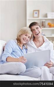 Laughing young couple with laptop at home