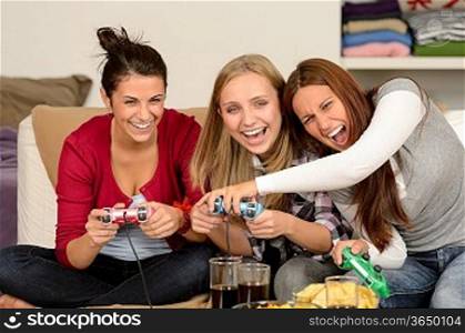 Laughing young girls playing with video games at home