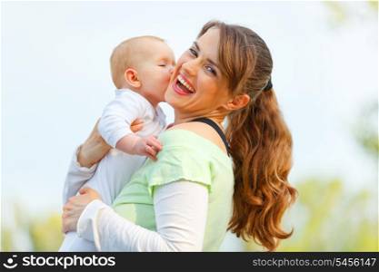 Laughing young mother hugging her baby in hands outdoors&#xA;