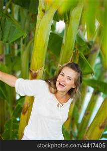 Laughing young woman among tropical palms