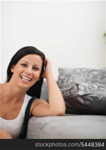 Laughing young woman sitting near sofa