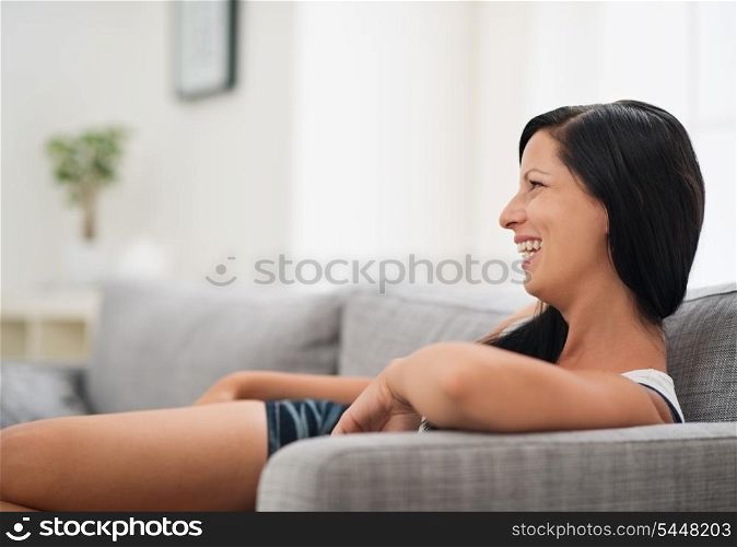 Laughing young woman sitting on couch in living room