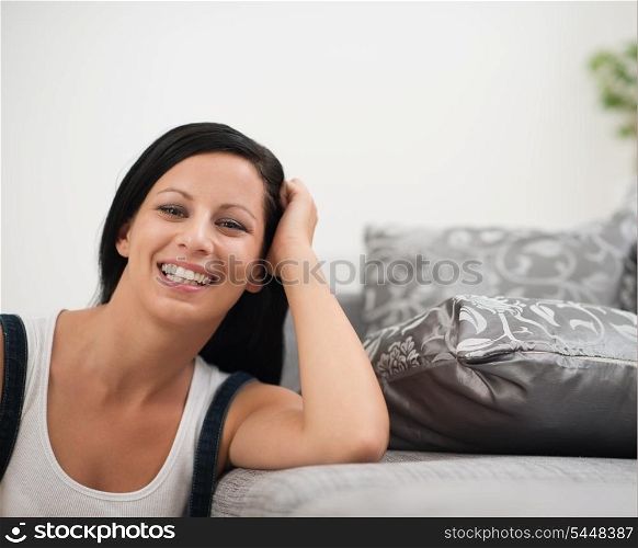 Laughing young woman sitting on floor near sofa