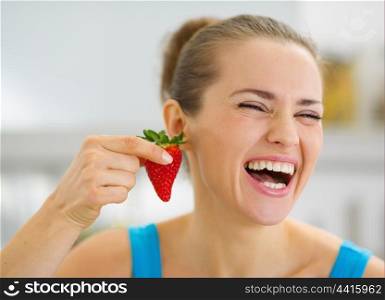 Laughing young woman using strawberry as earring