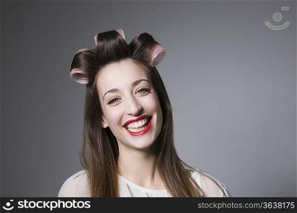 Laughing young woman with hair curlers and red lipstick
