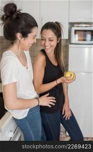 laughing young women couple standing kitchen