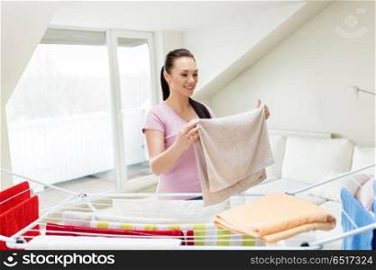 laundry and household concept - happy woman or housewife taking bath towels from drying rack at home. woman taking bath towels from drying rack at home. woman taking bath towels from drying rack at home