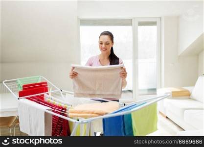 laundry and household concept - happy woman or housewife taking bath towels from drying rack at home. woman taking bath towels from drying rack at home. woman taking bath towels from drying rack at home