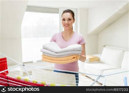 laundry and household concept - happy woman or housewife with drying rack holding bath towels drying rack at home. woman with bath towels and drying rack at home. woman with bath towels and drying rack at home