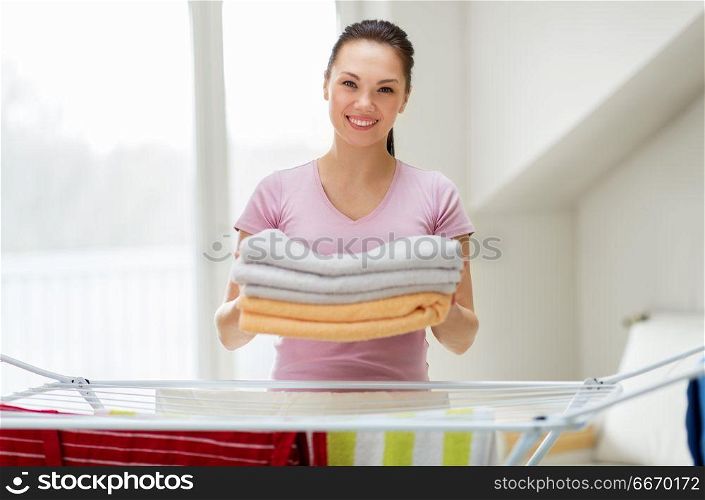 laundry and household concept - happy woman or housewife with drying rack holding bath towels at home. woman with bath towels and drying rack at home. woman with bath towels and drying rack at home