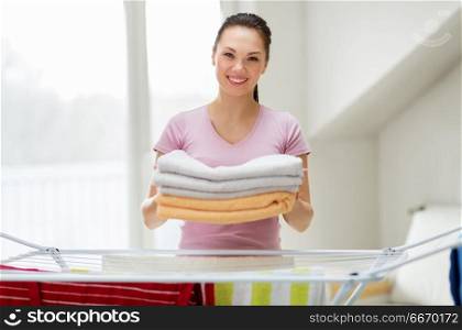 laundry and household concept - happy woman or housewife with drying rack holding bath towels at home. woman with bath towels and drying rack at home. woman with bath towels and drying rack at home