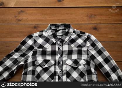 laundry, clothes, fashion and objects concept - close up of checkered shirt on wooden background