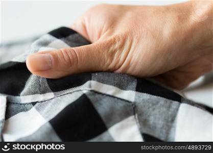 laundry, clothes, fashion and people concept - close up of hand with checkered clothing item