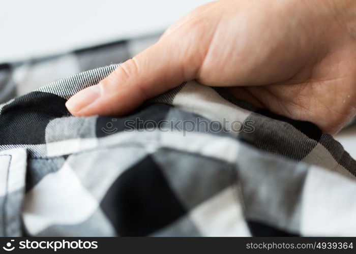 laundry, clothes, fashion and people concept - close up of hand with checkered clothing item. close up of hand with checkered clothing item