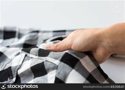 laundry, clothes, fashion and people concept - close up of hand with checkered clothing item. close up of hand with checkered clothing item