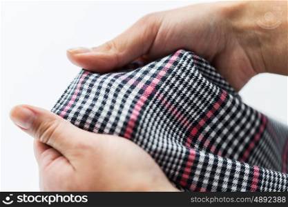 laundry, clothes, fashion and people concept - close up of hands with checkered clothing item