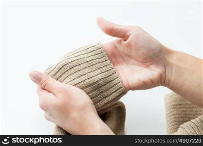laundry, clothes, fashion, knitwear and people concept - close up of hands with sweater sleeve or knitted clothing item. close up of hands with sweater sleeve