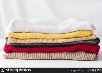 laundry, clothing, household and objects concept - close up of stacked knitted clothes