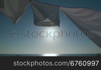 Laundry drying on clothesline against blue sky and sun