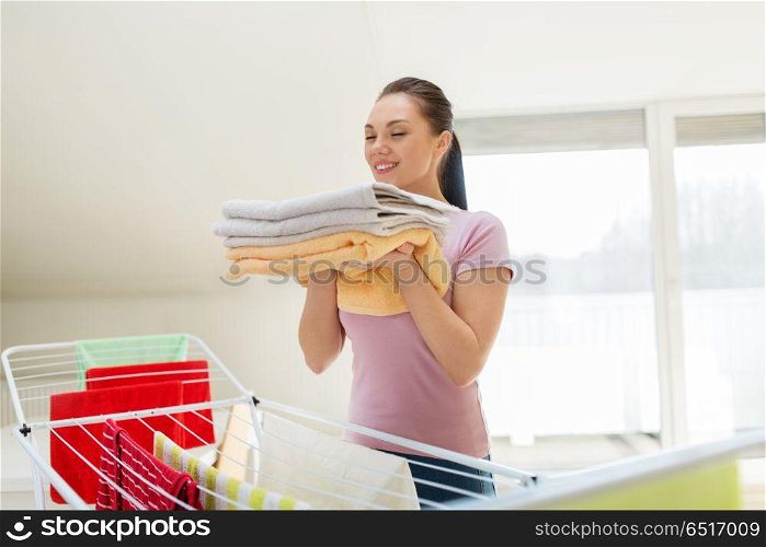 laundry, freshness and household concept - happy woman or housewife with drying rack holding fresh bath towels at home. woman with bath towels and drying rack at home. woman with bath towels and drying rack at home