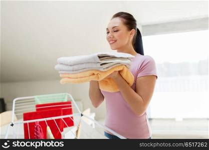 laundry, freshness and household concept - happy woman or housewife with drying rack holding fresh bath towels at home. woman with bath towels and drying rack at home. woman with bath towels and drying rack at home